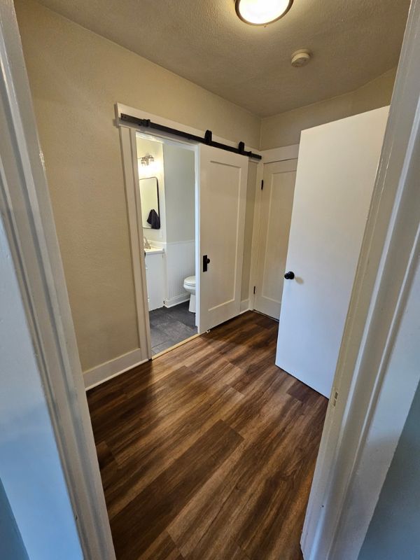 Hallway complete with new wood floors and a sliding barn door leading into the bathroom.