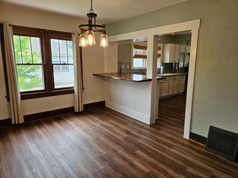 New flooring in a dining room area glistens beneath an industrial hanging light fixture.