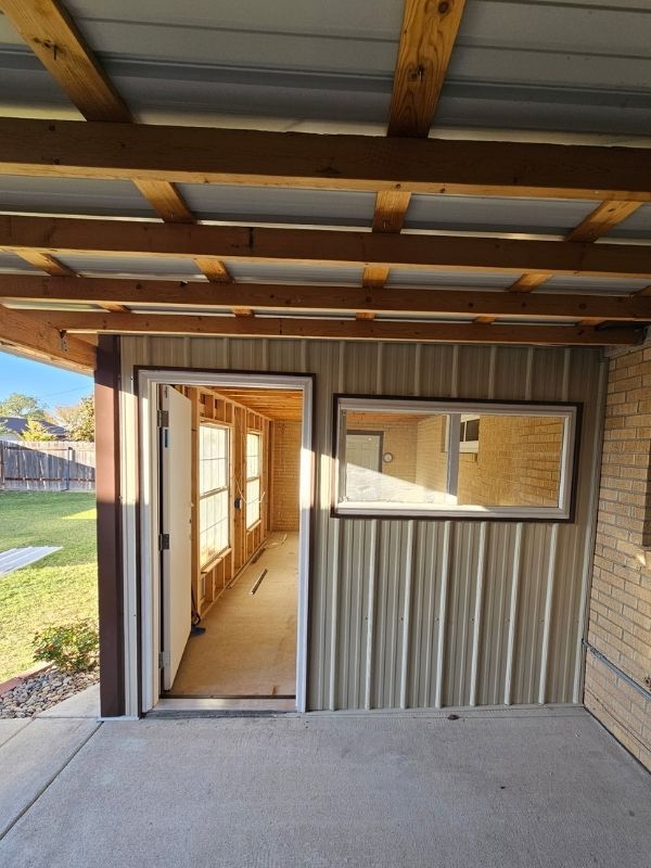 Interior view through the doorway of an enclosed patio set against a yellow brick house.