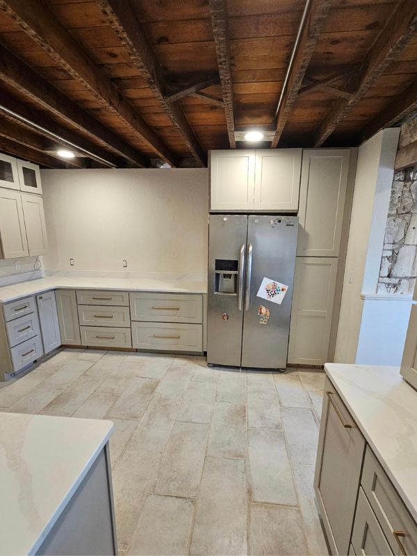 Tall pantry cabinets in a remodeled kitchen. Grey cabinets, gold handles, and an exposed wood accent ceiling complete the space.