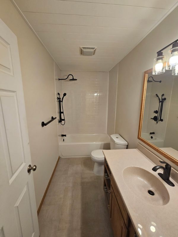 Bathroom remodeled by Seymour Construction LLC in Hays, Kansas featuring grey tile flooring, white Onyx shower, and shiplap ceiling.