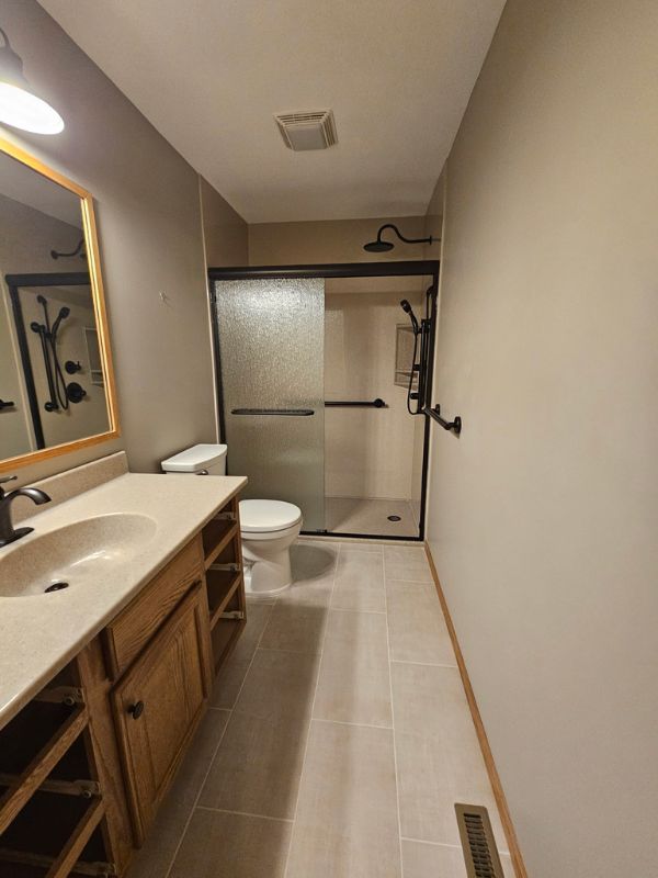 Updated bathroom in Hays, Kansas featuring a sliding glass shower door and black fixtures.