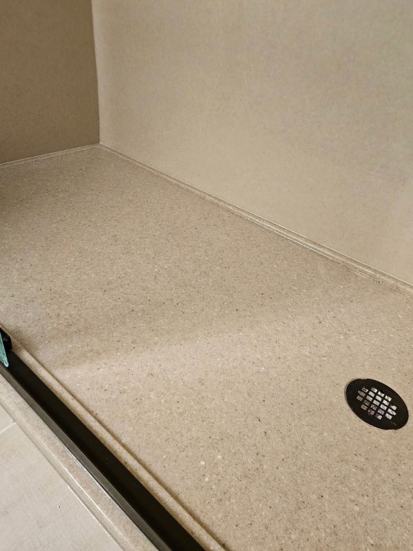 Clean and durable Onxy walk-in shower base in a speckled tan color completes a remodeled bathroom.