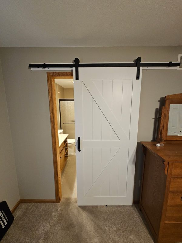 Rustic, white barn wood door slides to close off a remodeled bathroom in Hays, Kansas.