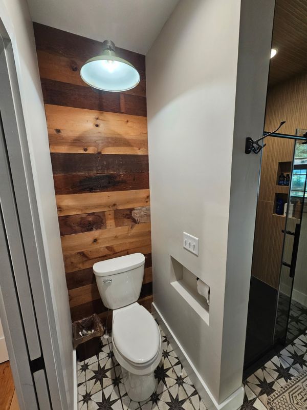 Rustic wood accent on the wall behind the toilet in a remodeled bathroom.