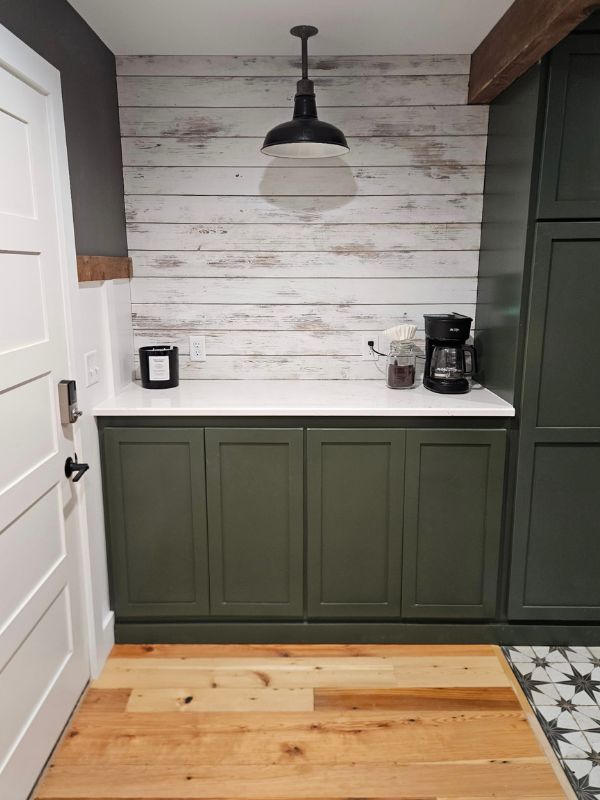 Coffee bar with custom green cabinets and distressed white shiplap wood as the backsplash.