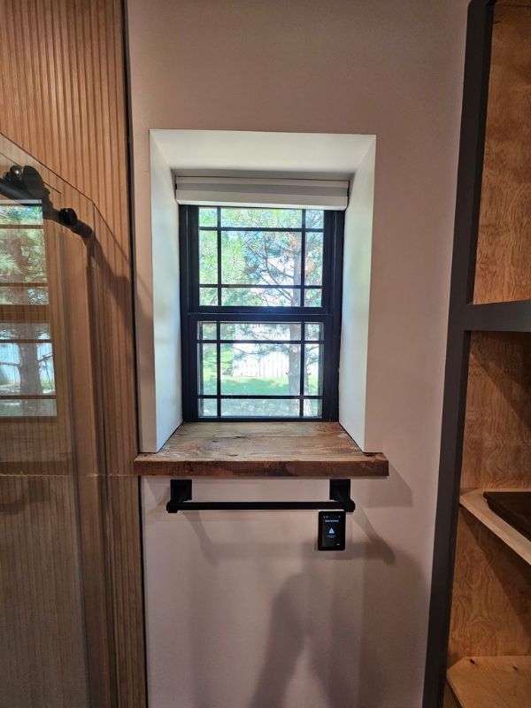 Rustic wood window sill in a remodeled bathroom.