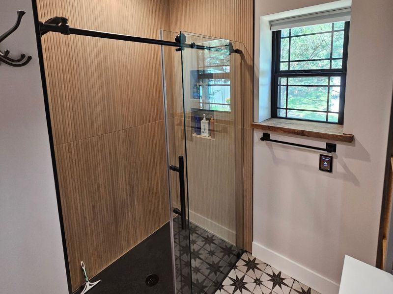 Bathroom addition in a Hays, Kansas home featuring vertical, tan tile in a shower and patterned flooring.