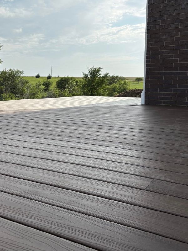 Neat flooring on a wrap around deck that circles a brick home in the country.