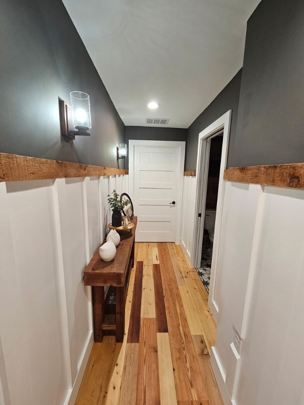 Hallway in a two bedroom, one bathroom addition. Hallway features grey paint and wood floors with a white accent wall.